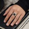 Cincin Pria Perak Bali Siver 925 Black Handmade Onyx Natural Signet Canero pada jari cowok di atas meja